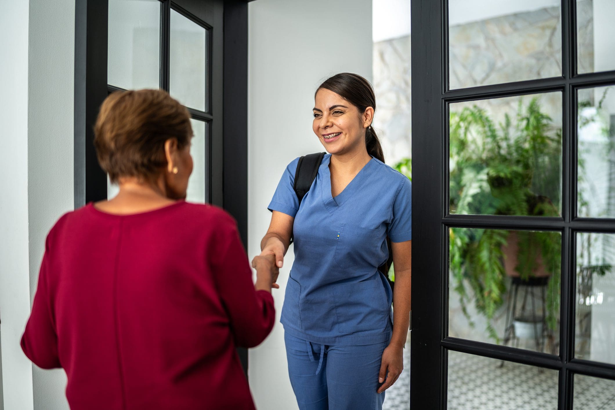Nurse greeting woman at the door.