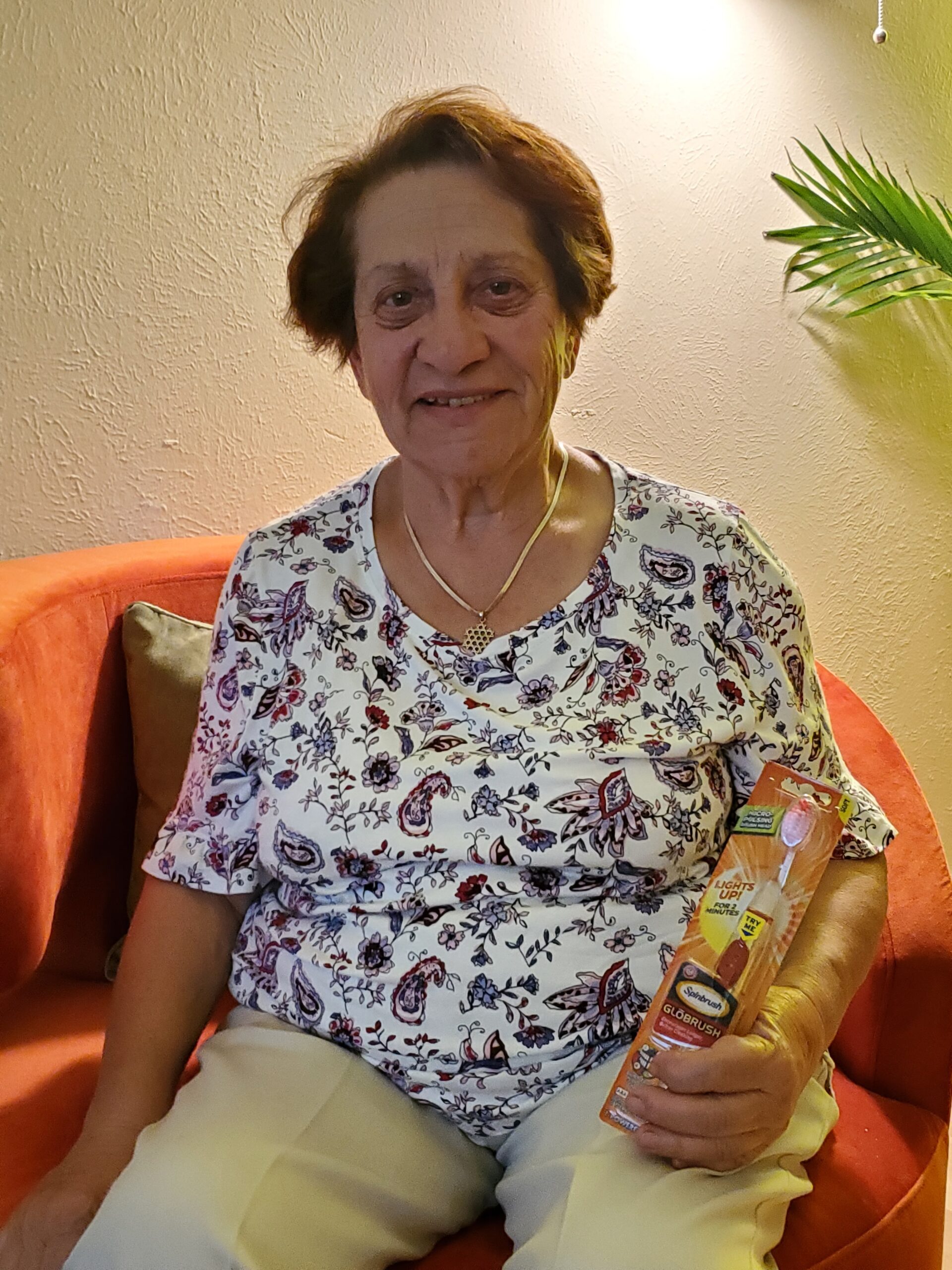 Smiling elderly woman seated holding packaged snack